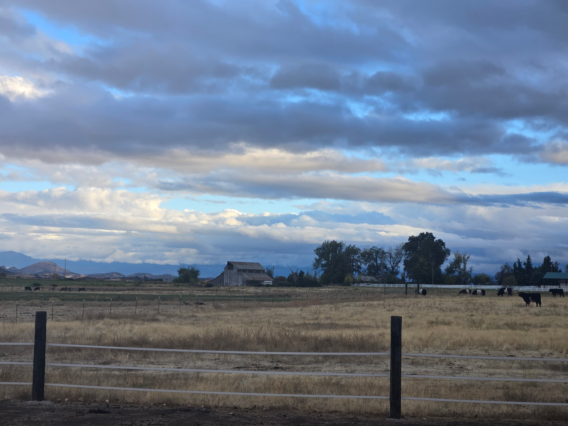 Weathered barn standing under a stormy fall sky, surrounded by open fields and distant hills — symbolizing steady faith.”