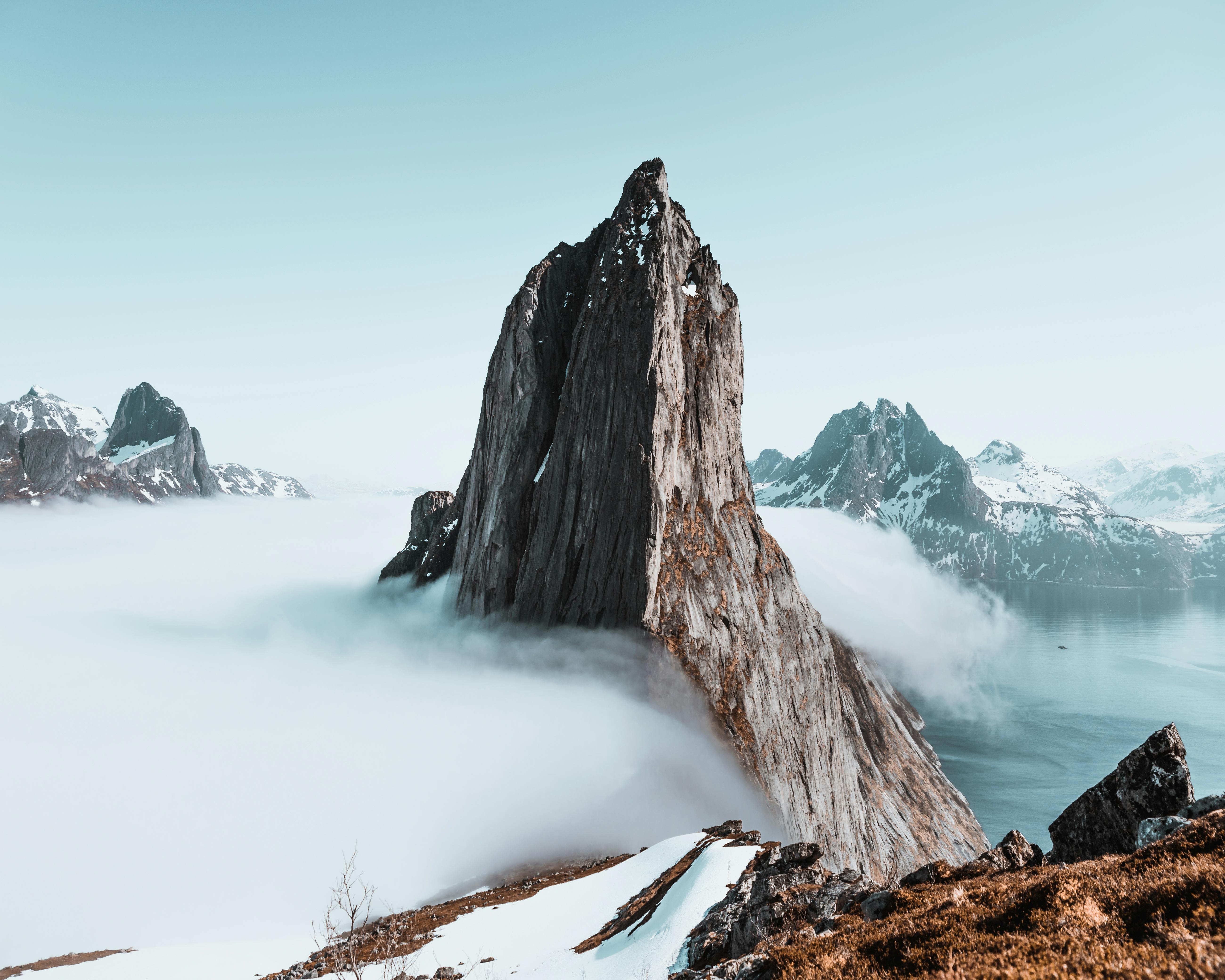 Epic winter landscape of sharp mountain peaks surrounded by mist in Troms, Norway.
